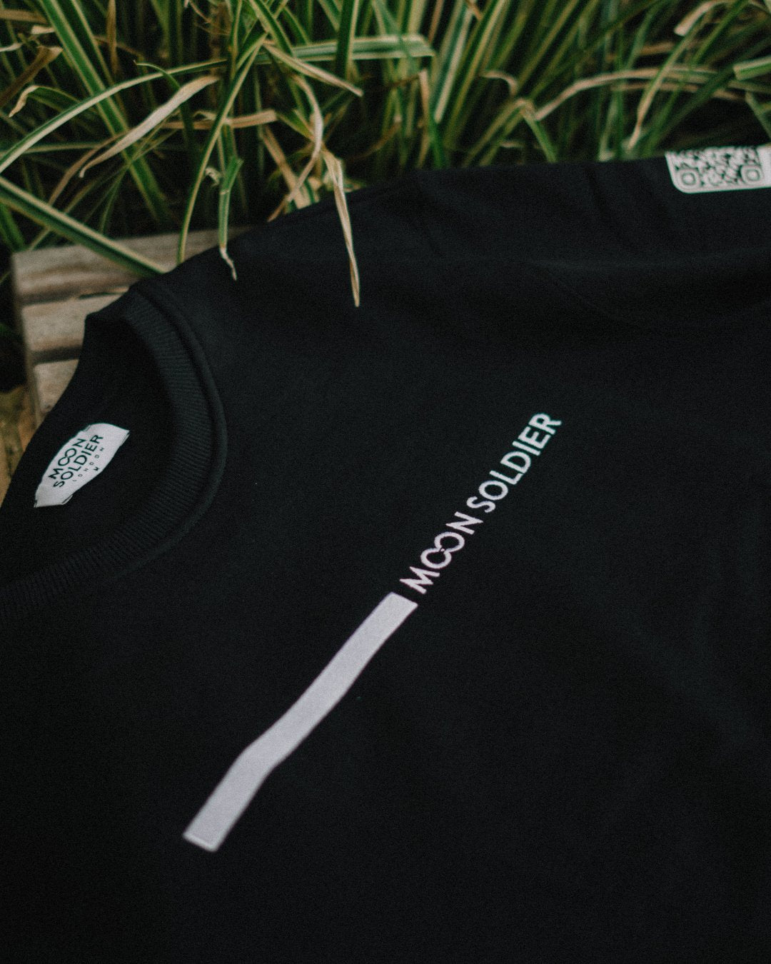 Close-up of Moon Soldier black sweatshirt with minimalist vertical linear logo design.
