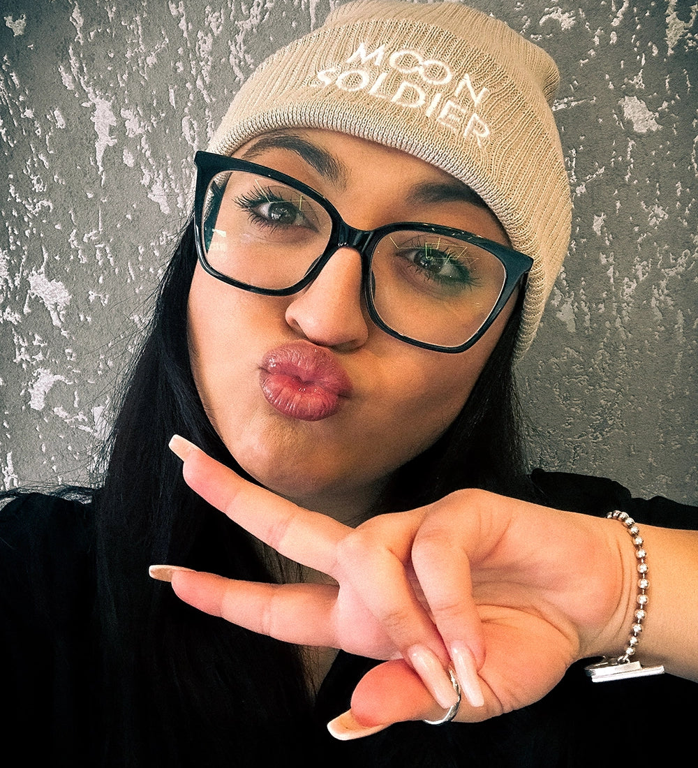 Model wearing a beige Moon Soldier soft cotton beanie, making a peace sign with a cozy and stylish vibe.