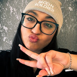 Model wearing a beige Moon Soldier soft cotton beanie, making a peace sign with a cozy and stylish vibe.